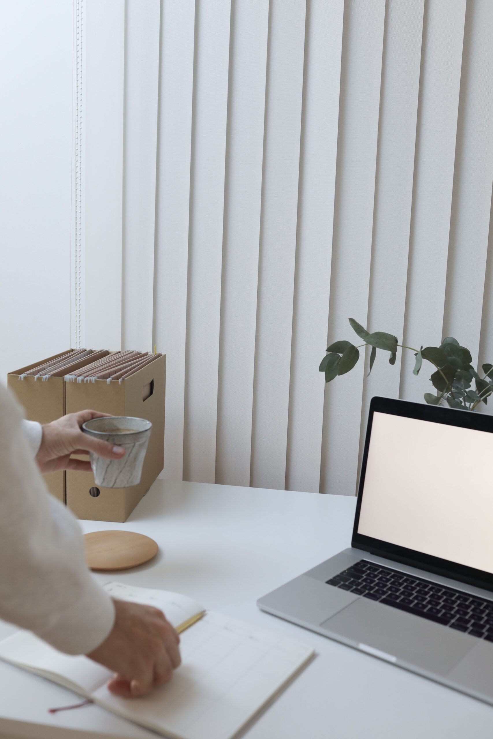 ノートPCとノート、コーヒーが置かれたデスクのイメージ写真